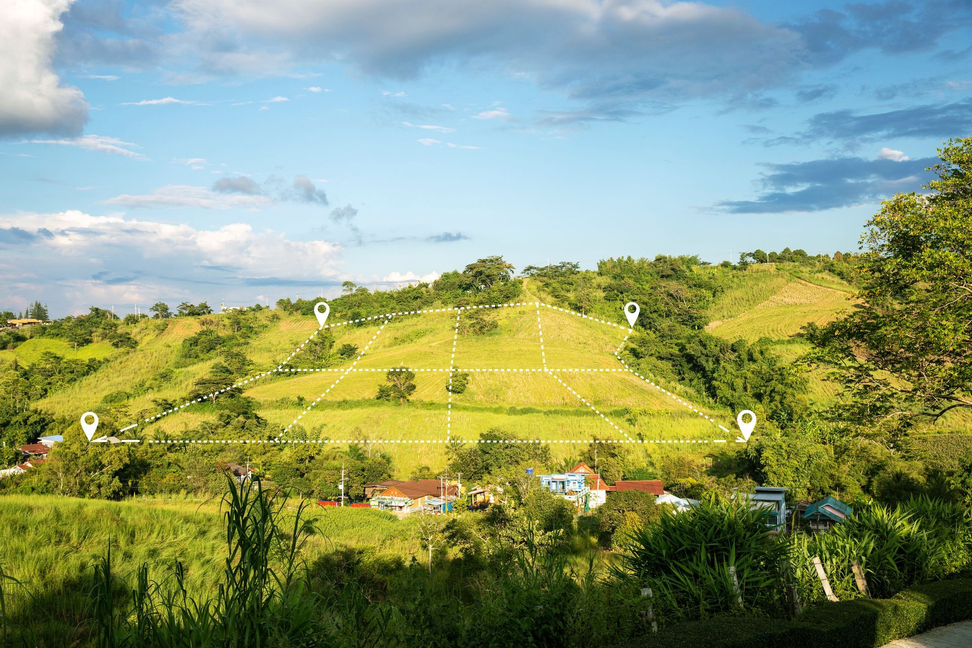 Paysage vallonné avec des parcelles délimitées, des lignes blanches et des bornes de localisation sous un ciel bleu nuageux.