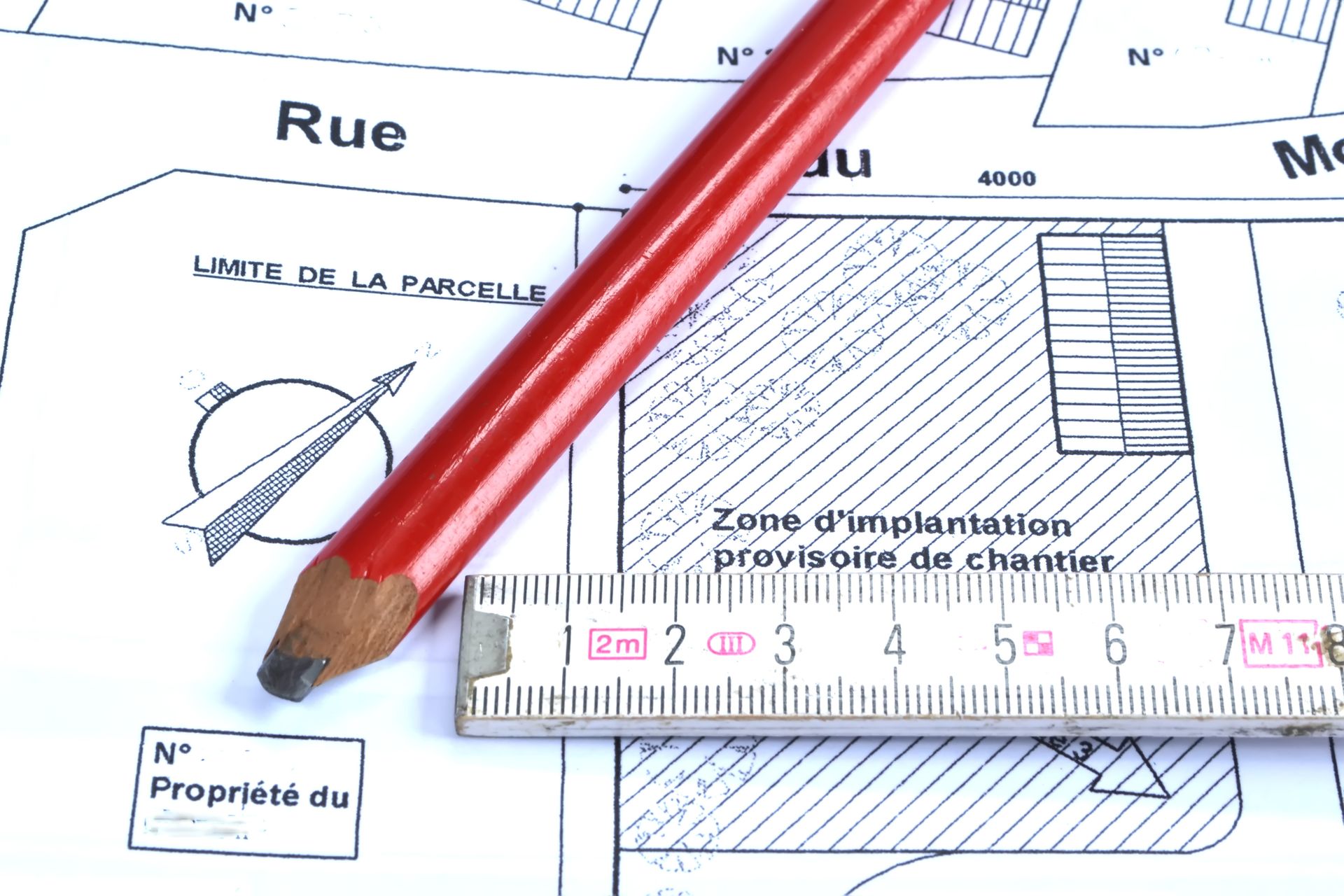 Crayon et règle sur un plan avec du texte en français.