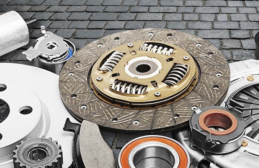 Diversas piezas de embrague y cojinetes de automóviles dispuestas sobre una superficie empedrada.
