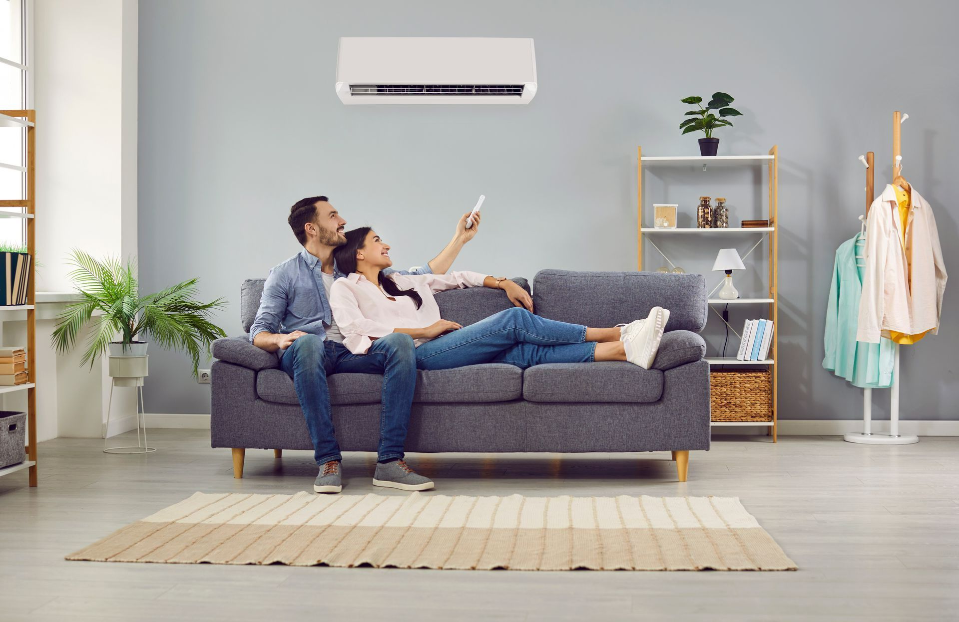 Un couple assis sur un canapé gris allume un climatiseur