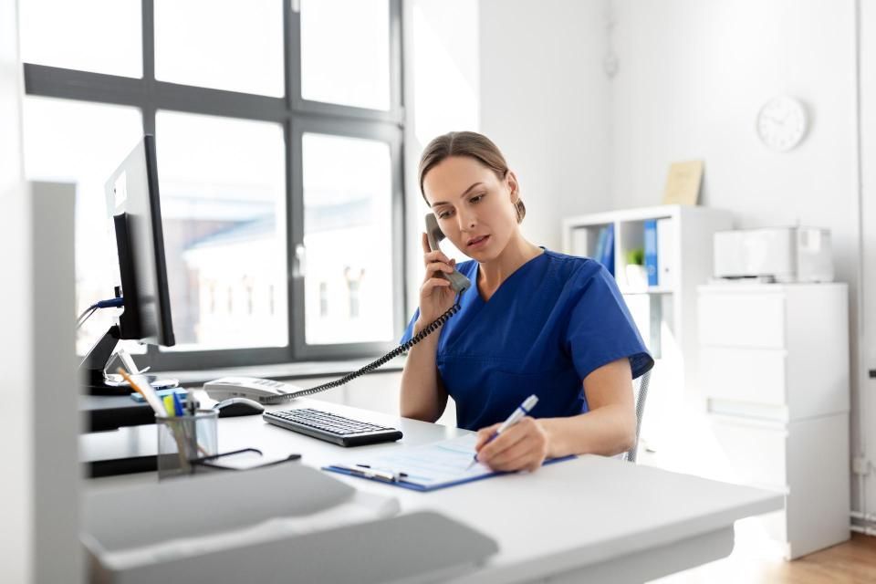 Pflegemitarbeiterin sitzt an einem Schreibtisch und telefoniert
