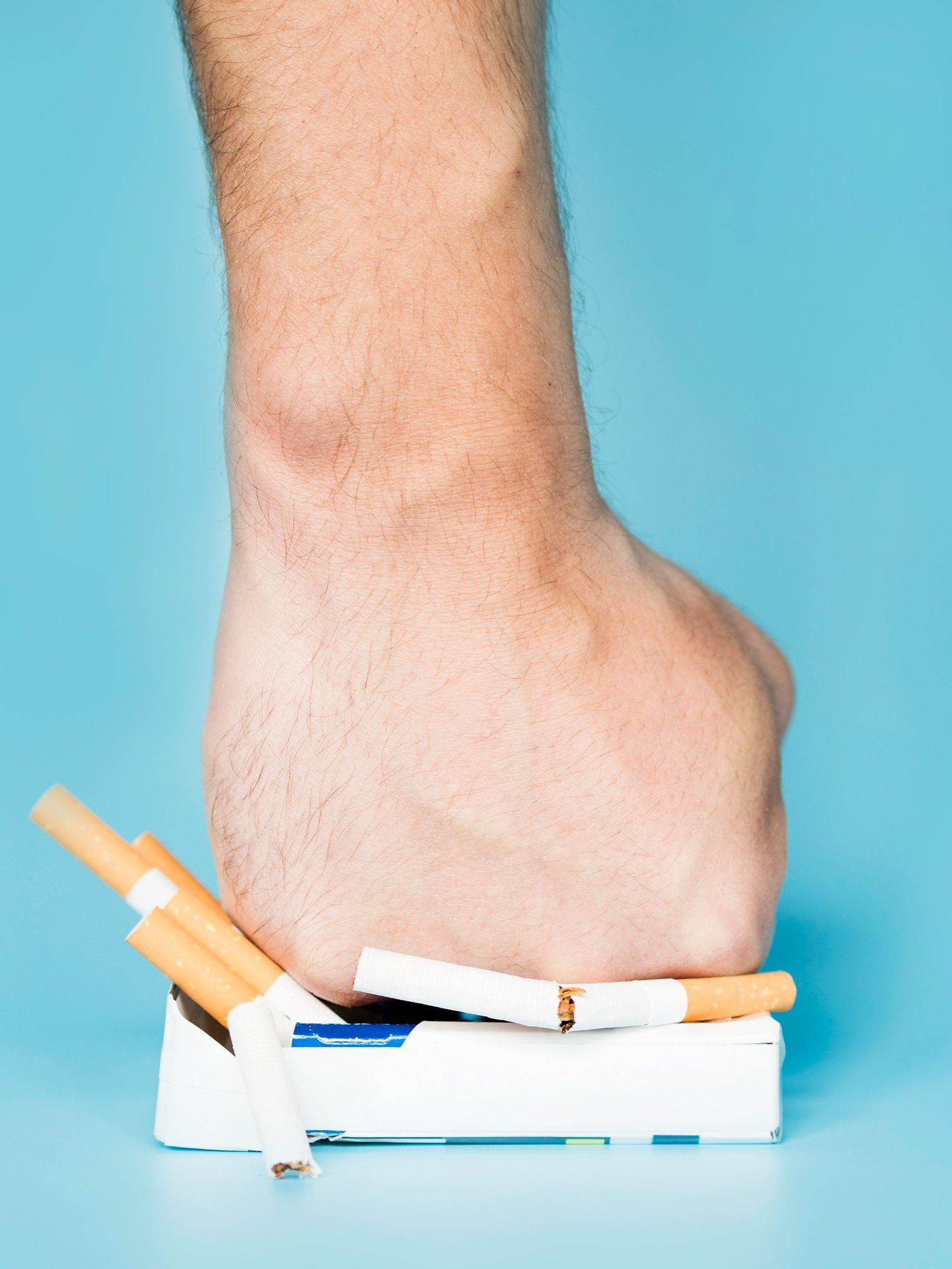 Un poing écrase un paquet de cigarettes