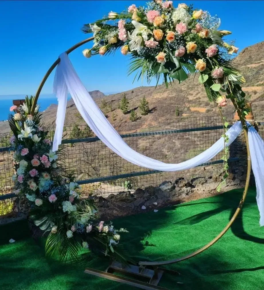Un arco circular decorado con flores y tela blanca.