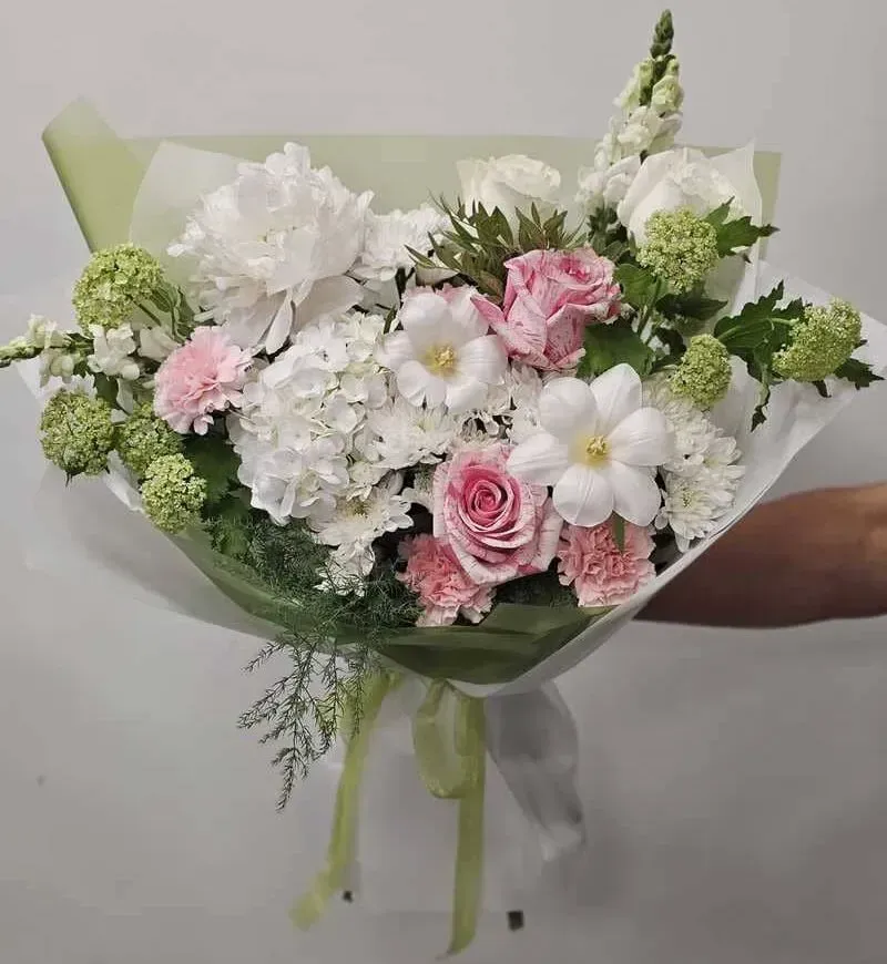 Una persona sostiene un ramo de flores blancas y rosas.