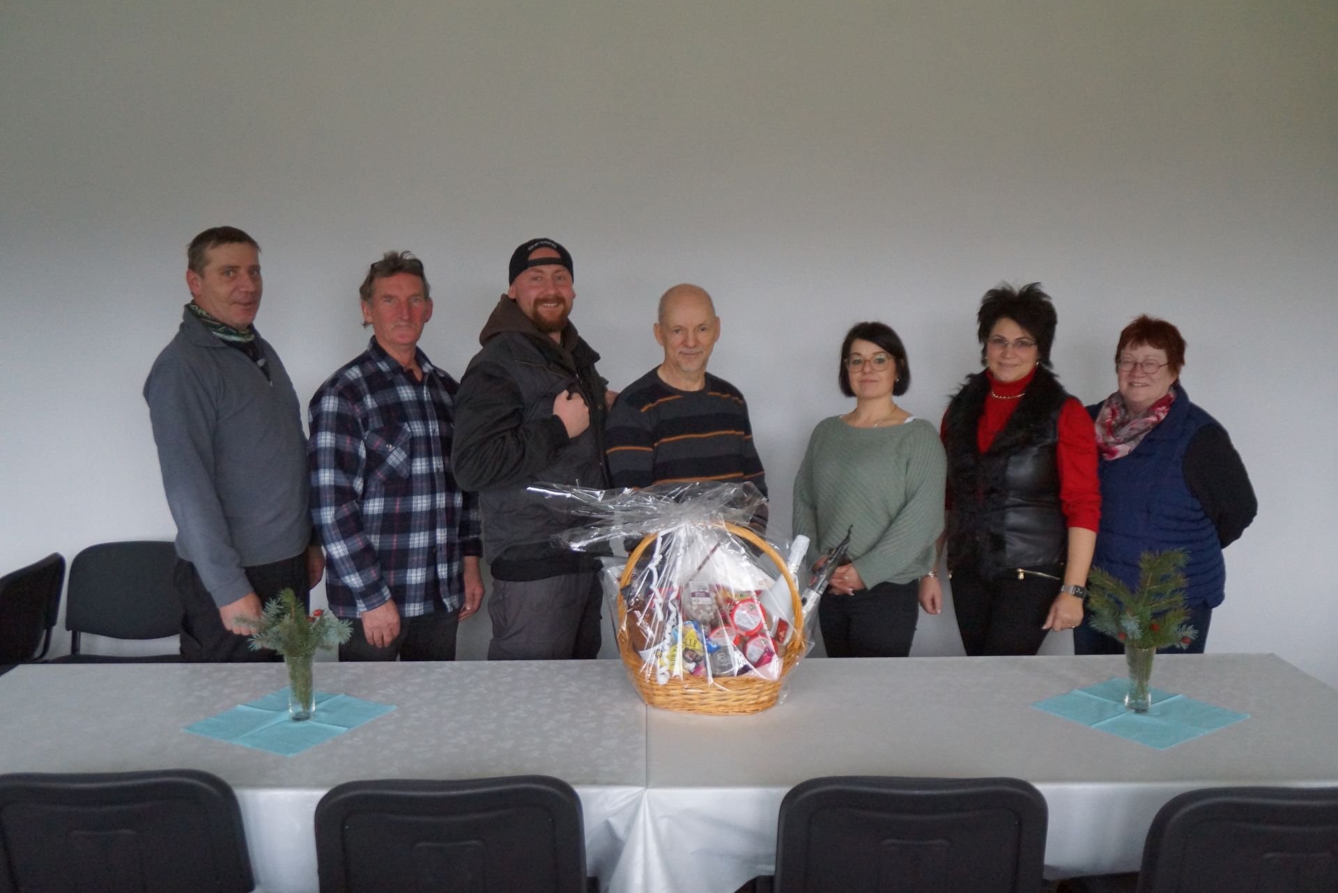 Eine Gruppe von Leuten steht um einen Tisch herum, auf dem ein Korb steht.