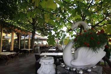 Außenbereich vom Pappas Alexandros Restaurant Olympia mit bepflanzter Schwanskulptur