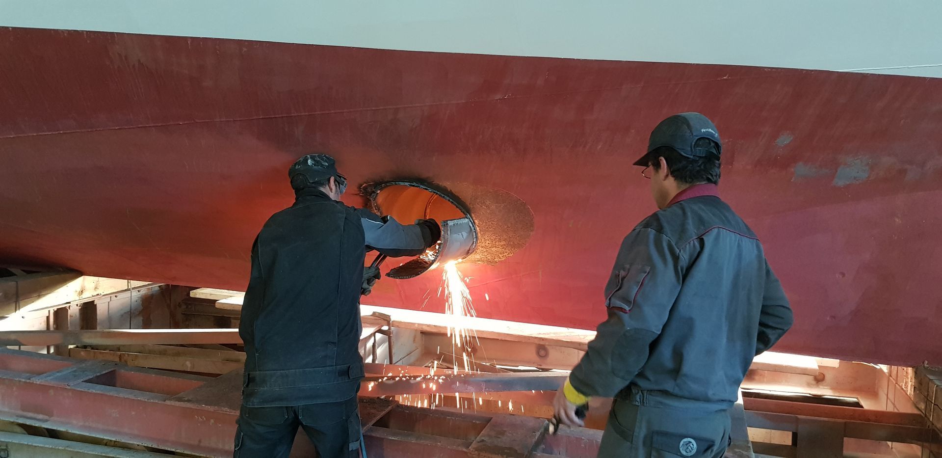 Ein Mann in einem orangefarbenen Overall benutzt in einem Kontrollraum ein Tablet.