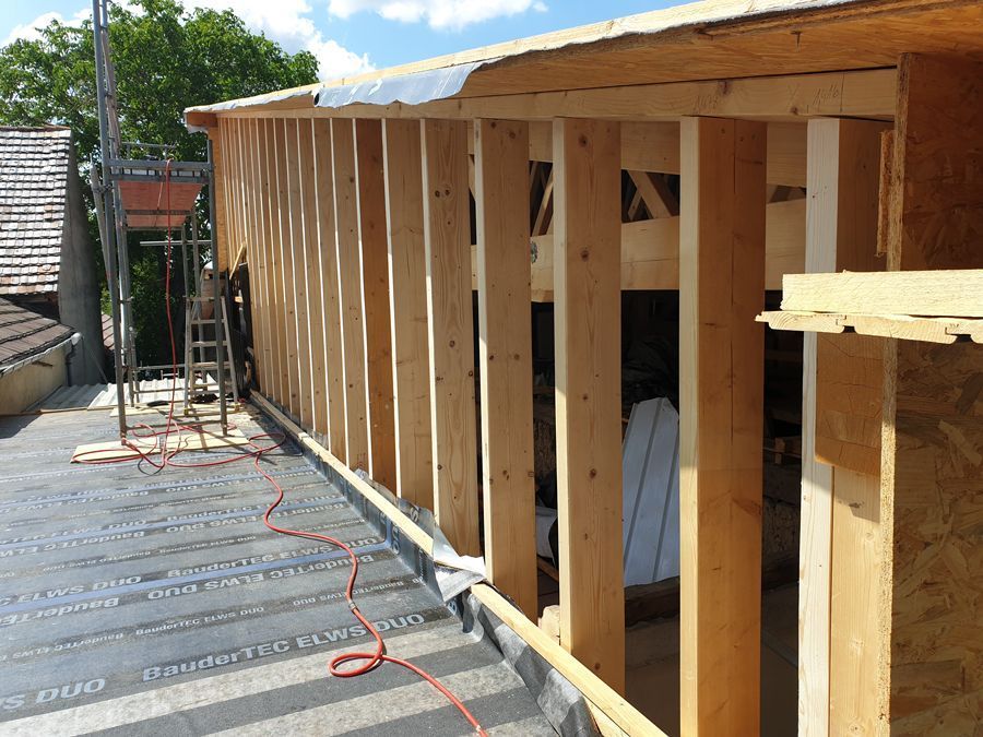 Auf einem Dach wird eine Holzkonstruktion errichtet.