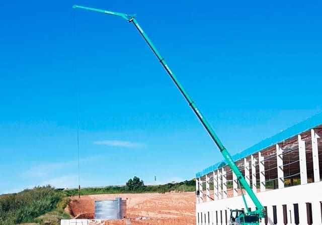 Una grúa verde está parada frente a un edificio en construcción.