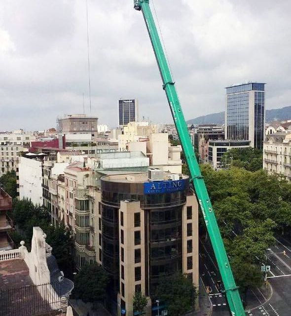 Una gran grúa verde está en medio de una ciudad.