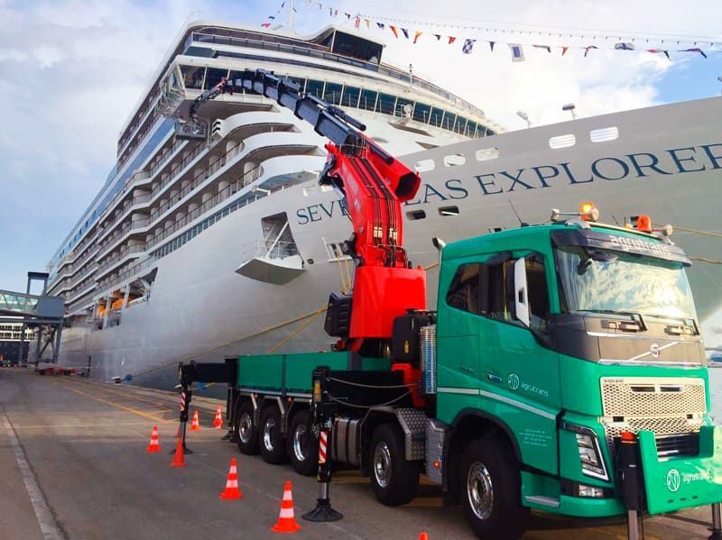 Un camión verde está estacionado frente a un gran crucero.