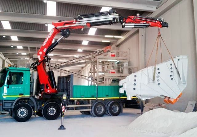 Un camión con una grúa acoplada está en un almacén.