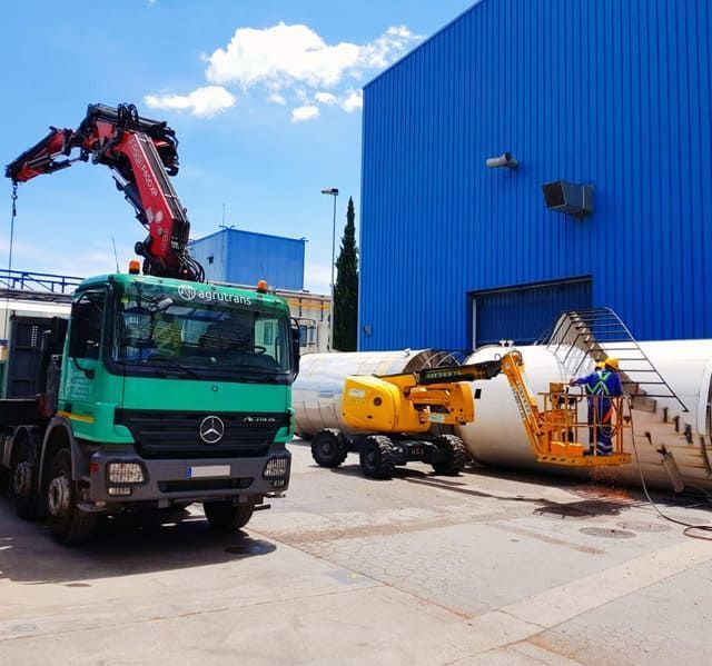 Un camión Mercedes verde está estacionado frente a un edificio azul.