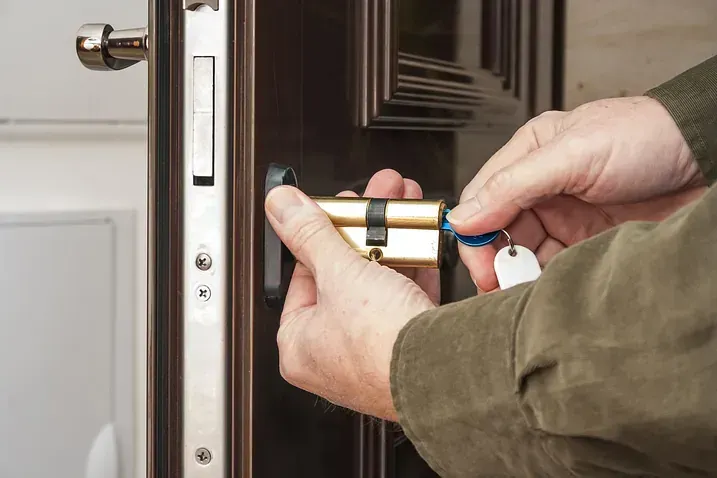 Un hombre está arreglando una cerradura de puerta con una llave.