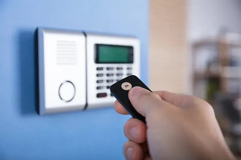 Una persona sostiene un control remoto frente a un sistema de seguridad.