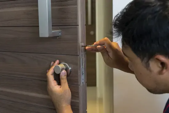 Un hombre está arreglando una puerta con un destornillador.