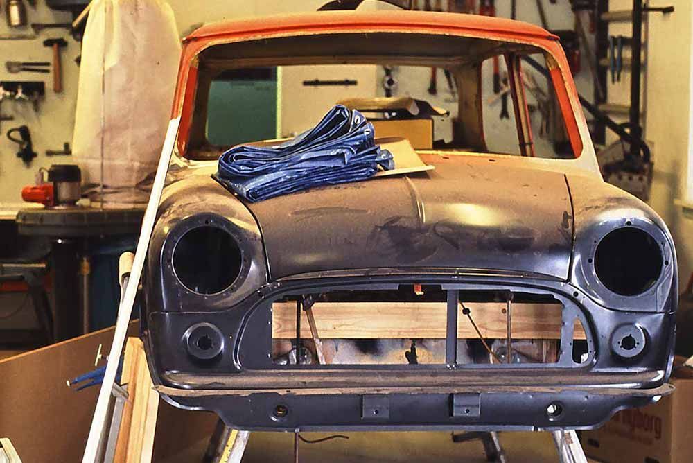 In einer Garage steht ein zerlegter alter Kleinwagen