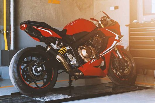 Ein rotes Motorrad steht auf einer Hebebühne in einer Garage.