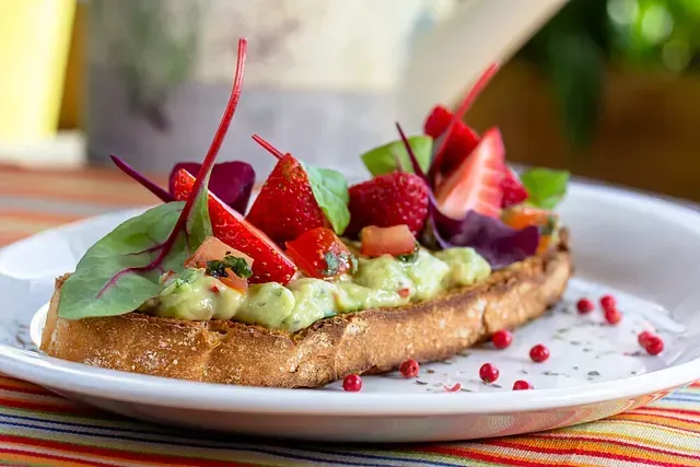 Un primer plano de un plato de comida con guacamole y fresas en una mesa.
