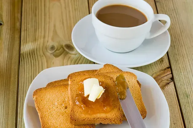 Un plato de tostadas con mantequilla y mermelada junto a una taza de café.