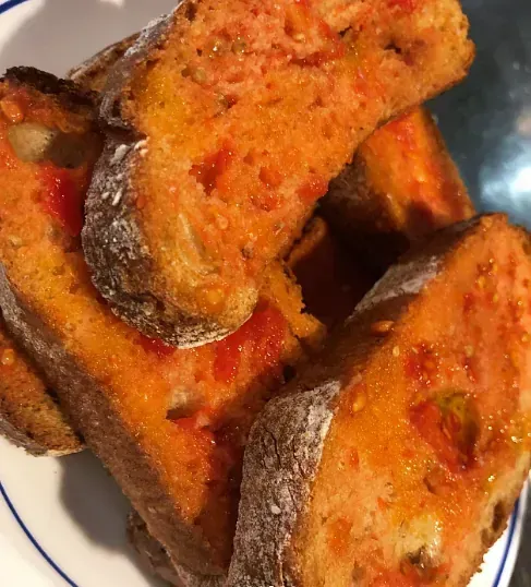 Un plato blanco cubierto con rebanadas de pan cubiertas con salsa de tomate.