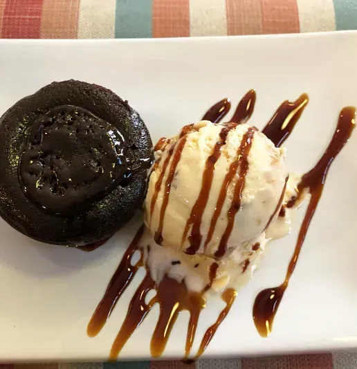 Un plato blanco cubierto con helado y un pastel de chocolate.