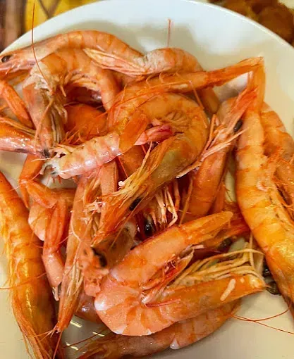 Un plato blanco cubierto de camarones sobre una mesa.