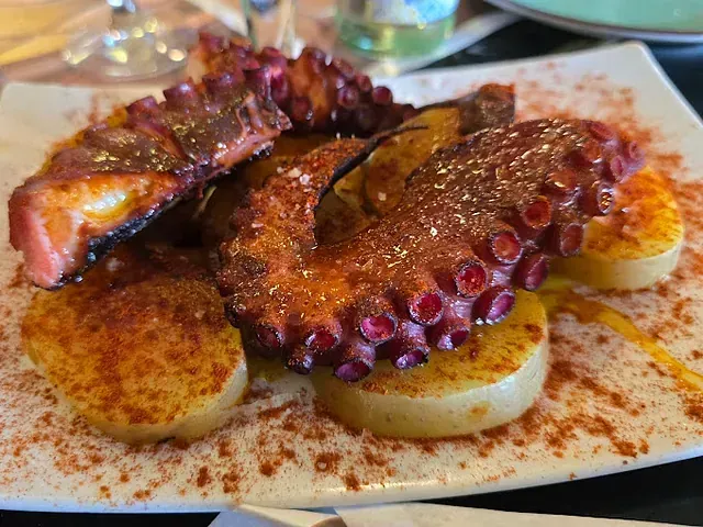 Un plato de comida con pulpo y patatas en una mesa.