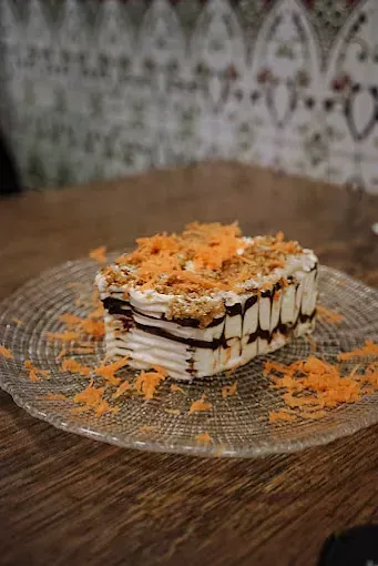 Un trozo de pastel de zanahoria en un plato de vidrio sobre una mesa.