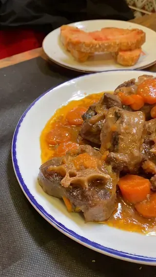 Un primer plano de un plato de comida con zanahorias y carne sobre una mesa.