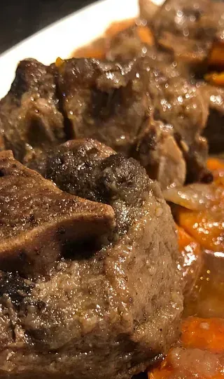 Un primer plano de un plato de carne y zanahorias en una mesa.