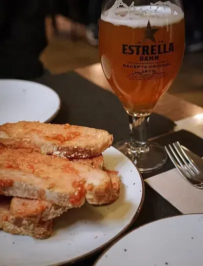 Un vaso de cerveza Estrella junto a un plato de comida