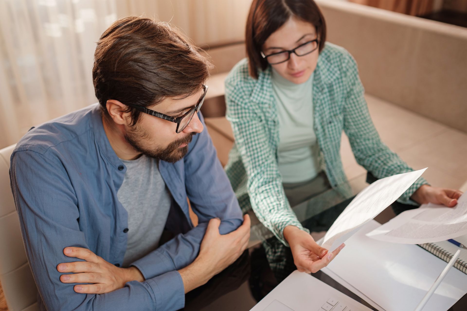 Hombre y mujer revisando documentos juntos, ambos con gafas.