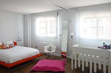 Un dormitorio con cama, silla, cuna y espejo.