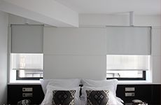 Un dormitorio con una cama y dos ventanas con persianas.