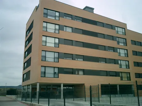 Un edificio grande con muchas ventanas y una valla alrededor.