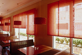 Un restaurante con persianas rojas en las ventanas.