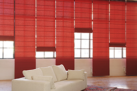 Una sala de estar con persianas rojas y un sofá blanco.