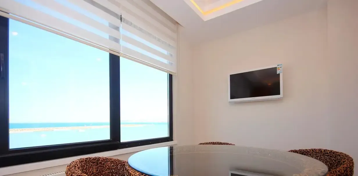 Hay una mesa y sillas en la habitación con una ventana grande.
