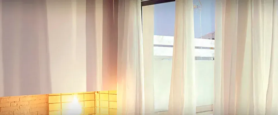 Una habitación con cortinas blancas y una lámpara.