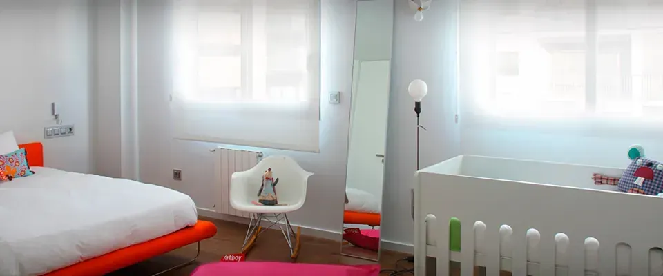 Un dormitorio con cama, silla, cuna y espejo.