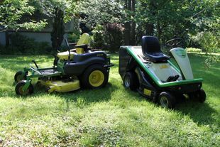 Zwei Aufsitzrasenmäher auf dem Rasen: ein John Deere und ein grün-schwarzer Viking.