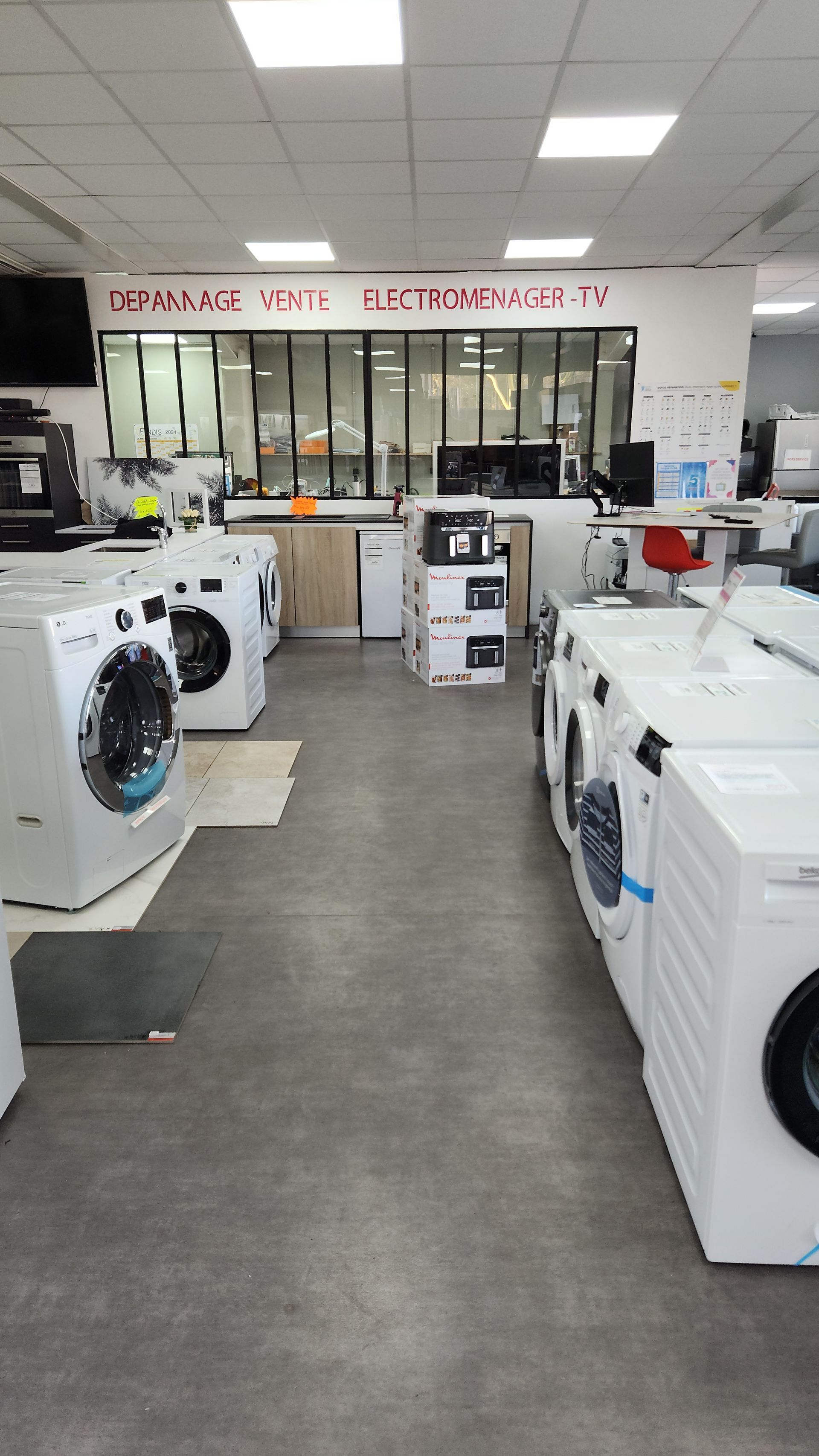 Un magasin présente diverses machines à laver blanches. Quelques appareils électroménagers sont visibles à l'arrière-plan