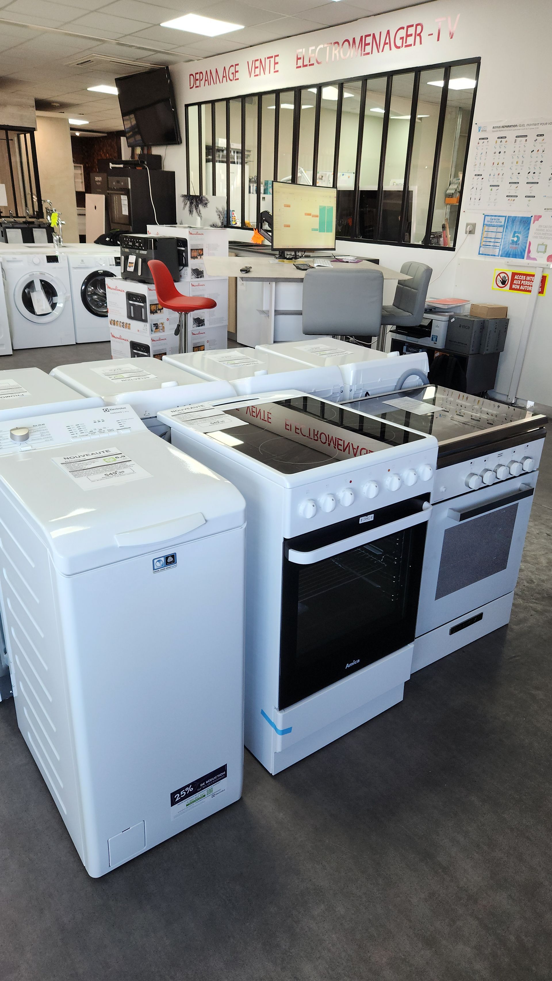 Appareils électroménagers exposés dans un magasin. Lave-linge et fours blancs au premier plan, autres appareils à l'arrière-plan.