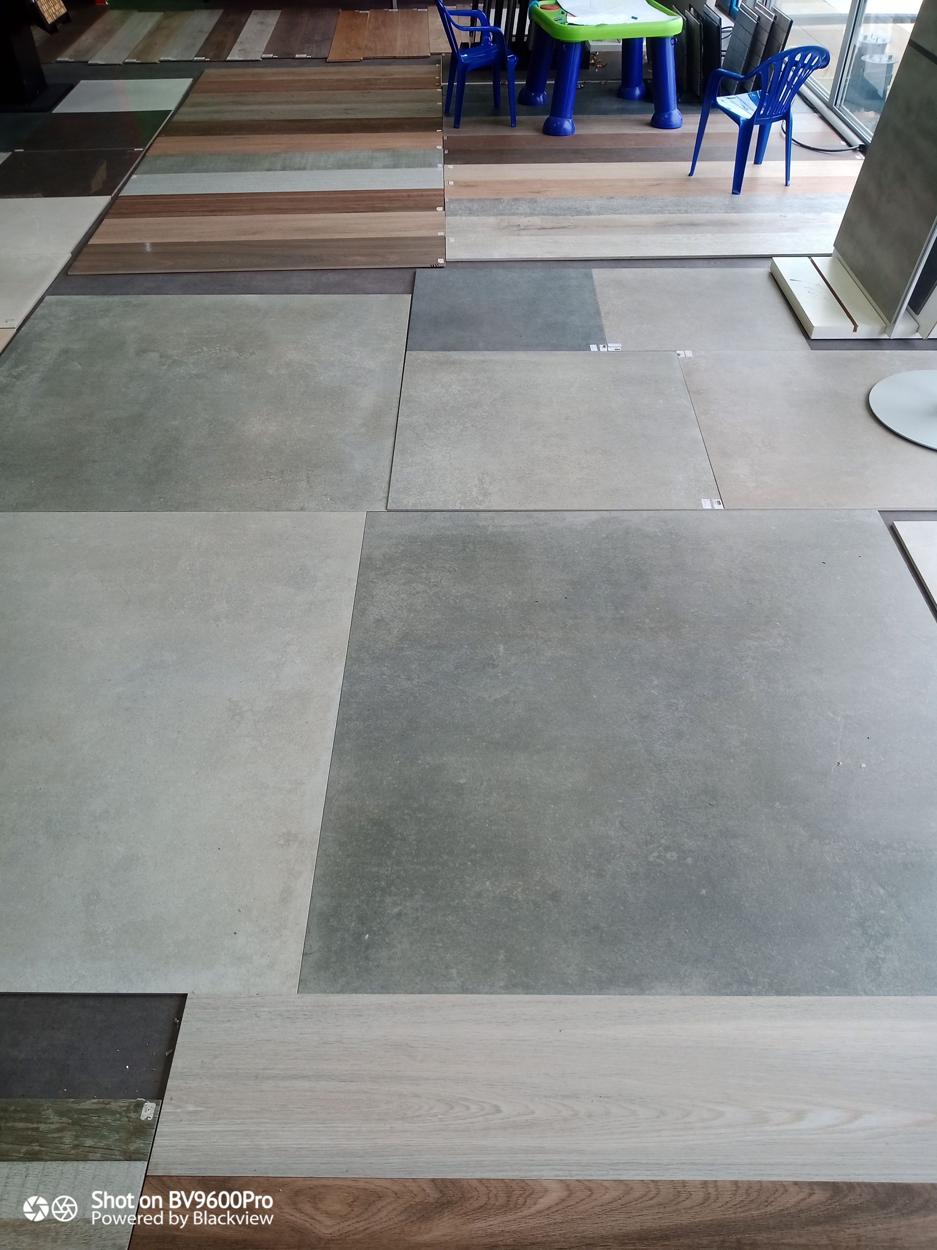 Échantillons de carreaux de sol de différentes couleurs et textures, en salle d'exposition.