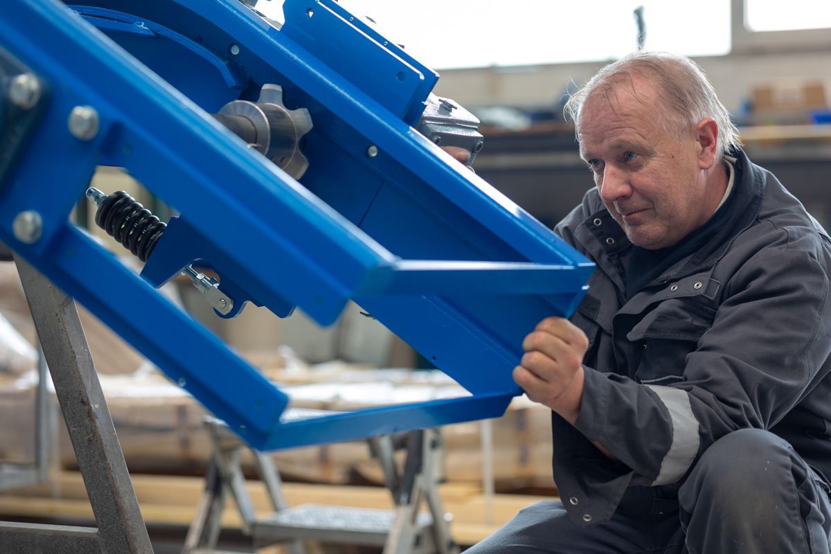 Ein Mann arbeitet in einer Werkstatt an Maschinen aus blauem Metall.