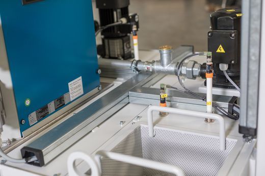 Nahaufnahme von Komponenten einer Industriemaschine: ein blauer Kasten, Motoren, Sensoren und ein Metallrahmen.