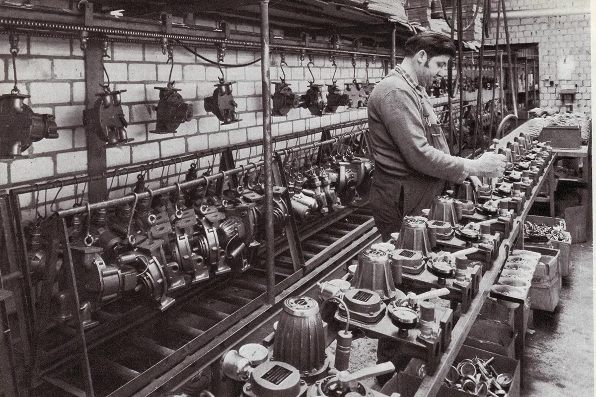 Ein Fabrikarbeiter montiert Ausrüstung und konzentriert sich dabei auf die Teile auf einer Werkbank in einem von Ziegelwänden umgebenen Raum.
