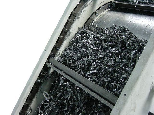 Metallspäne auf einem industriellen Förderband, innerhalb eines Metallgehäuses.