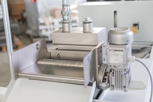 Industriemaschine aus Edelstahl mit Motor und Walzen, vermutlich zur Materialverarbeitung.